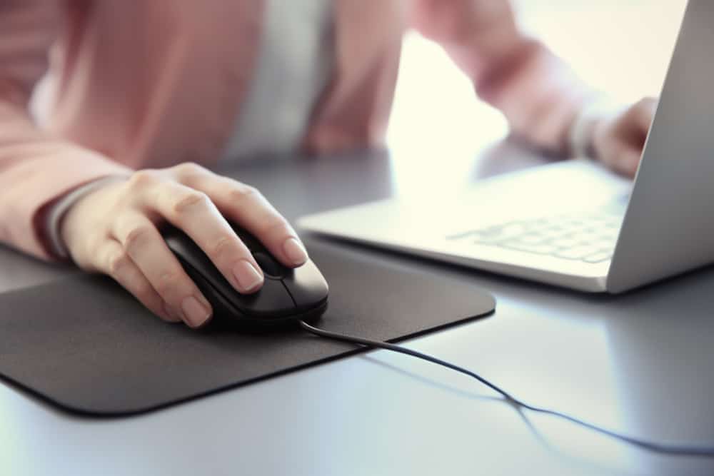 Woman Using Laptop With Wired Mouse On The Table