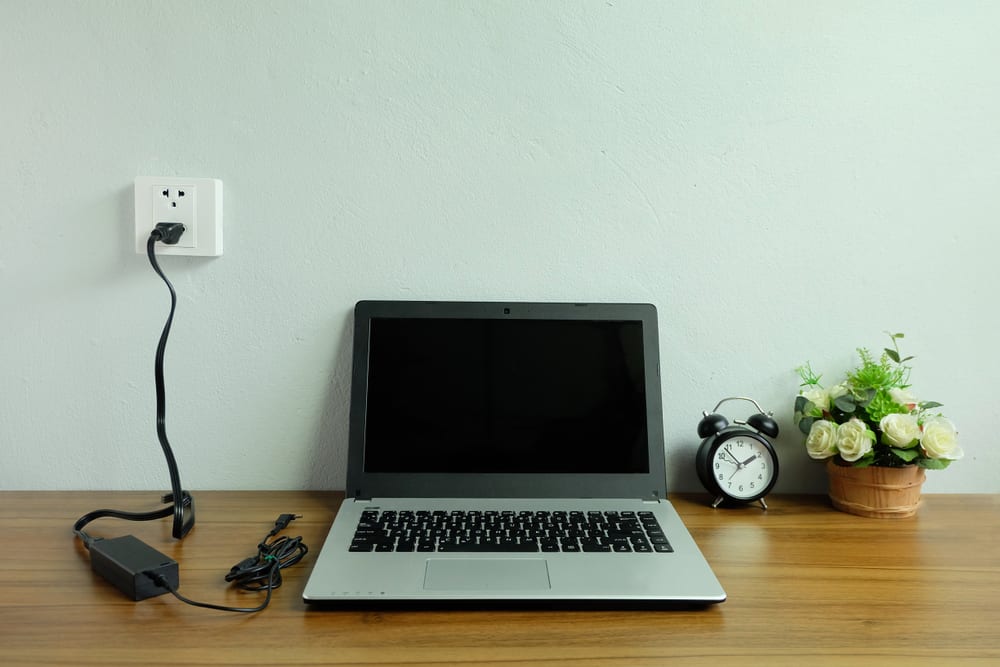 Laptop on a Desk with a Charger Plugged in